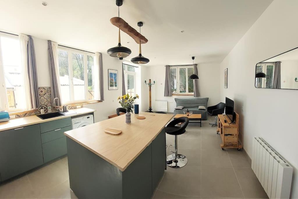 a kitchen with a island in the middle of a room at L'aigrette moderne, ensoleillé et bien placé in Thury-Harcourt