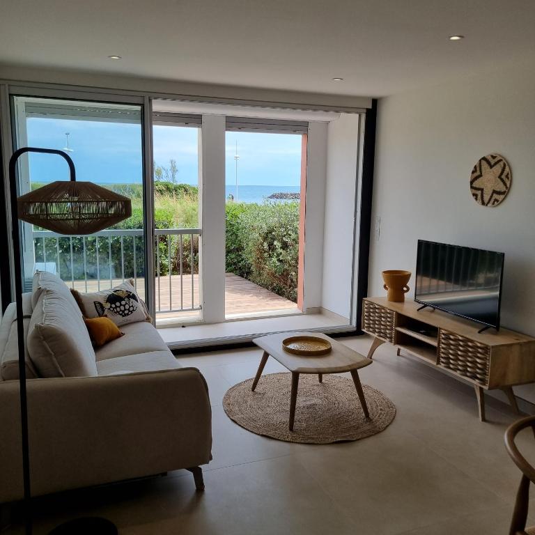 Il comprend un salon avec un canapé, une télévision et un balcon. dans l'établissement Coté Mer, au Cap d'Agde