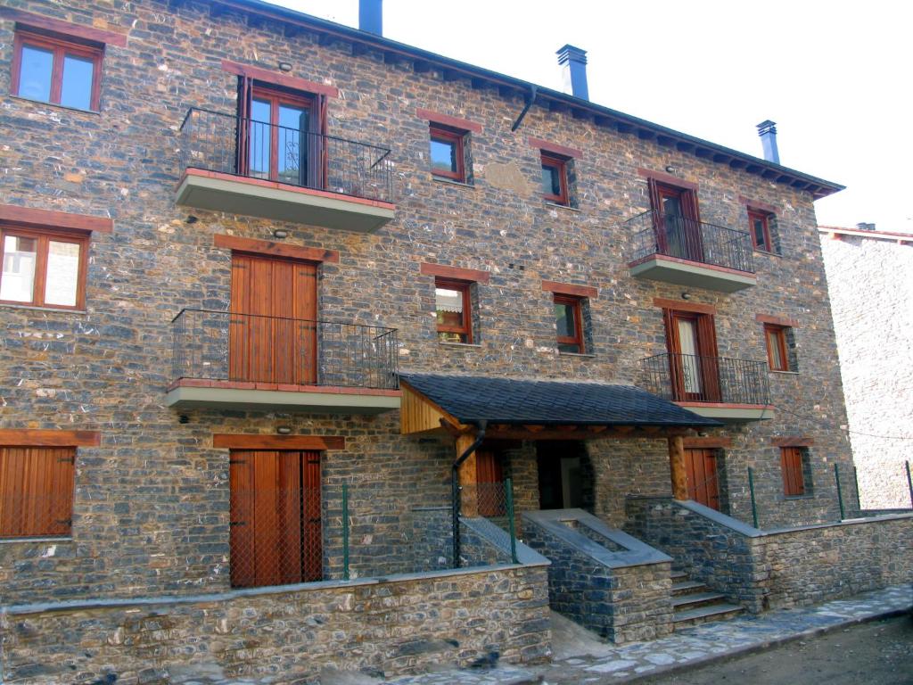 a large brick building with wooden doors and stairs at Les LLaus in Ribera de Cardós
