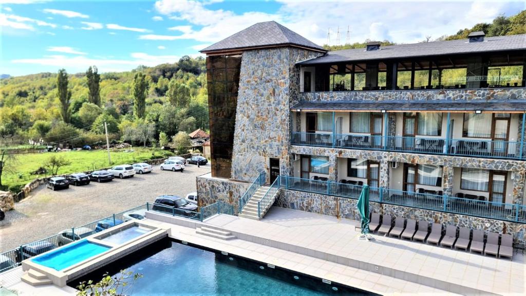 a building with a swimming pool next to a parking lot at Tskaltubo Epic Hotel & Spa in Tsqaltubo