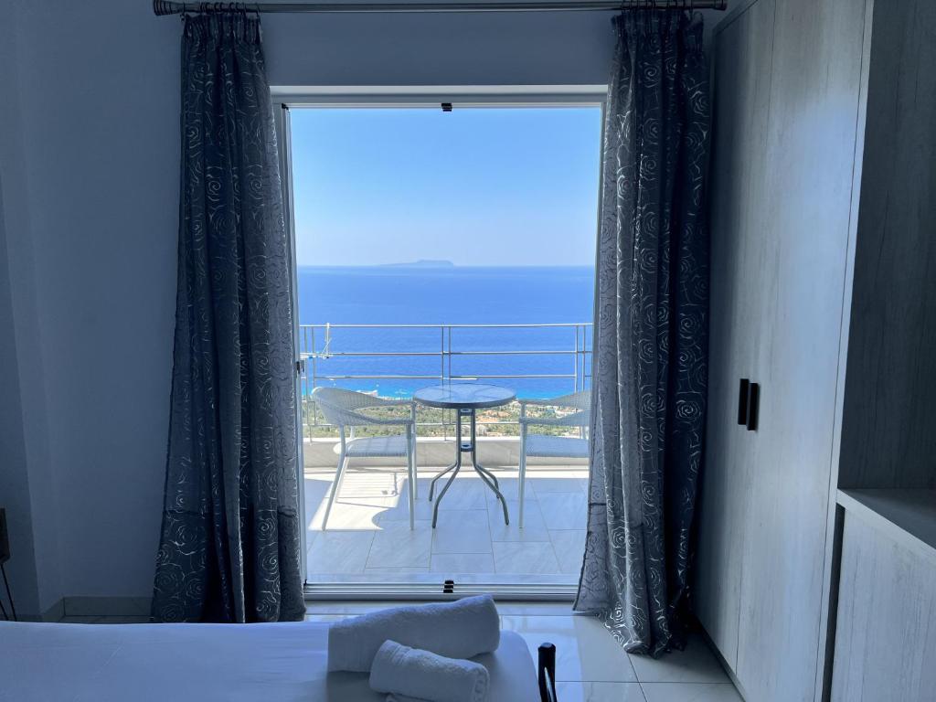 a room with a window with a table and a balcony at Palasa View in Dhërmi