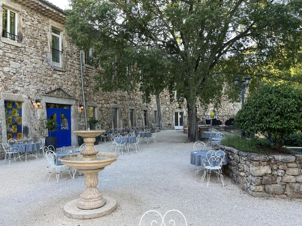 ein Steingebäude mit einem Brunnen sowie Tischen und Stühlen in der Unterkunft Logis Hôtel Restaurant Le Domaine de l'Eau Vive in Largentière