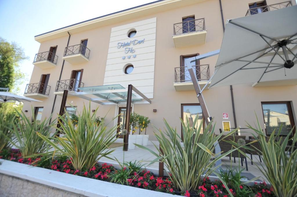 un bâtiment avec un parasol devant lui dans l'établissement Hotel Dori, à Peschiera del Garda