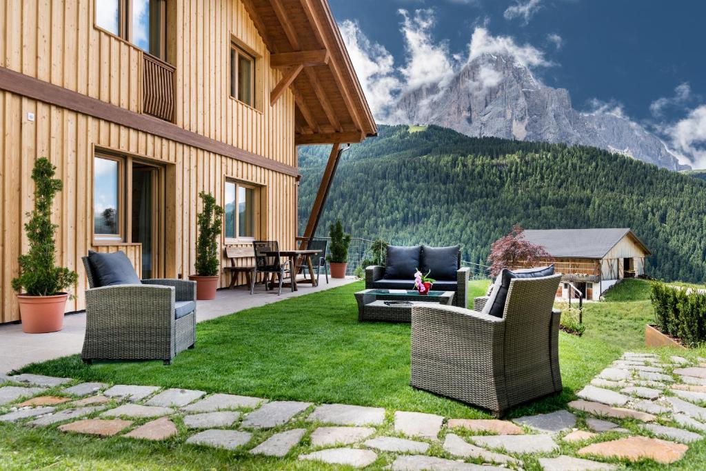 a patio with chairs and a table with a mountain at Villa Solinda App Puccini in Selva di Val Gardena
