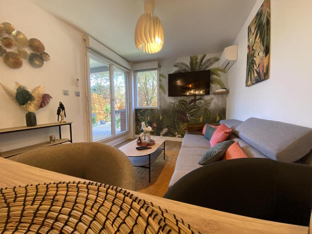 a living room with a couch and a tv at Le Jungle : T2 avec jardin et jacuzzi in Blagnac