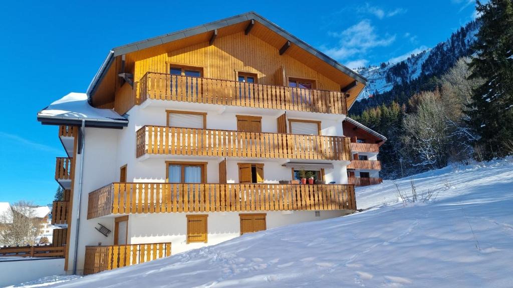 ein Gebäude mit Balkon im Schnee in der Unterkunft Chalet récent cœur station in Thollon