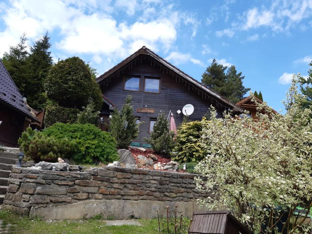 a house with a stone retaining wall in front of it at Chata Ľubka in Vyšné Ružbachy