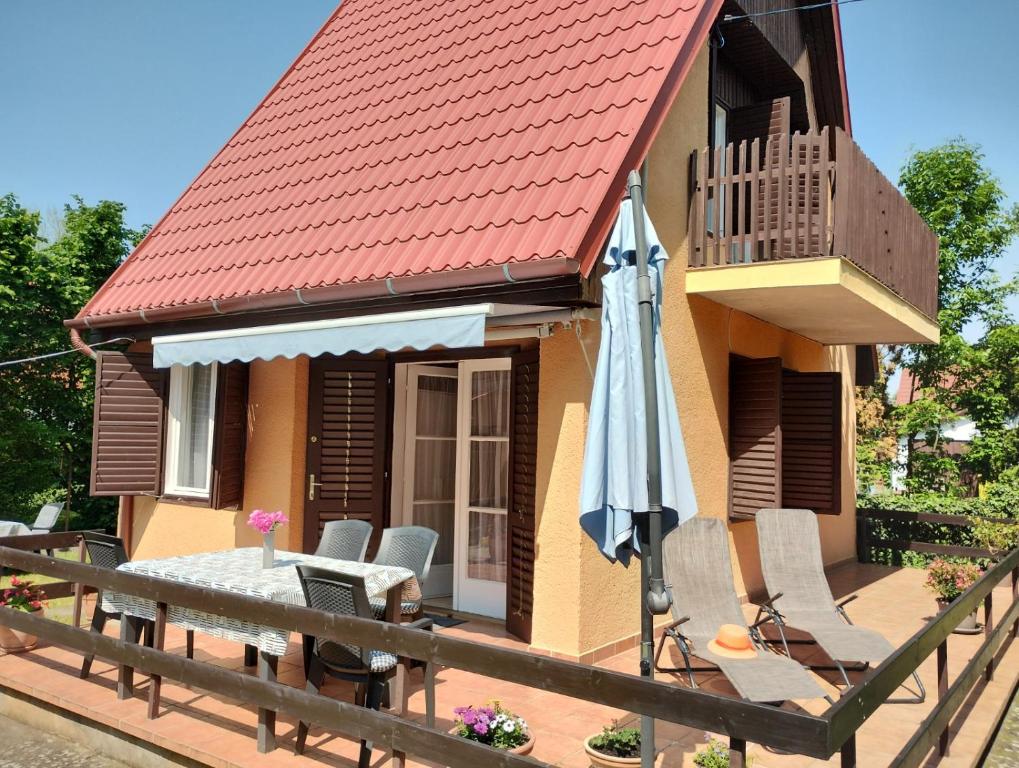 Casa pequeña con mesa y sombrilla en Tutijó Házikó, en Balatonfenyves