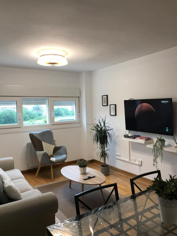 sala de estar con sofá, mesa y TV en Apartamentos Olga Cantabria, en Polanco
