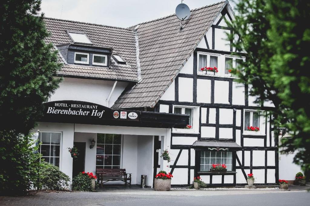 un edificio bianco e nero con una panchina davanti di Bierenbacher Hof a Nümbrecht