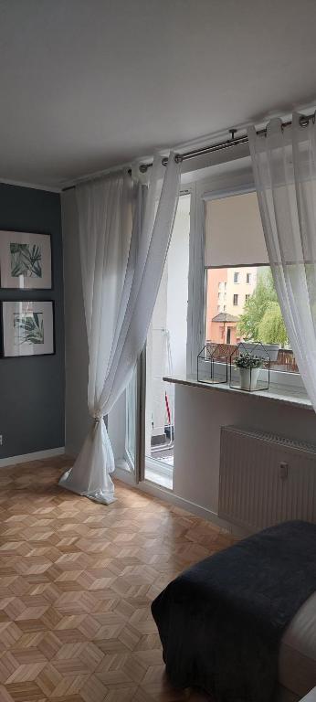 Schlafzimmer mit einem großen Fenster mit weißen Vorhängen in der Unterkunft Apartament Rodzinny Przy AquaParku in Reda