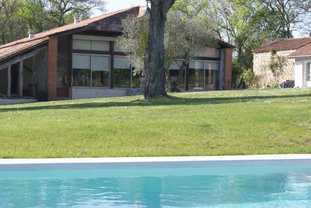 una casa con un árbol y una piscina en Le Domaine De Dolly, en Villeneuve-sur-Lot