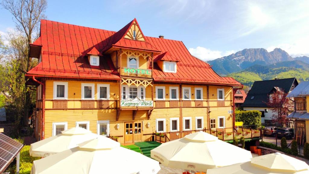 ein großes Haus mit rotem Dach und einigen Sonnenschirmen in der Unterkunft Resort Kasprowy Wierch in Zakopane