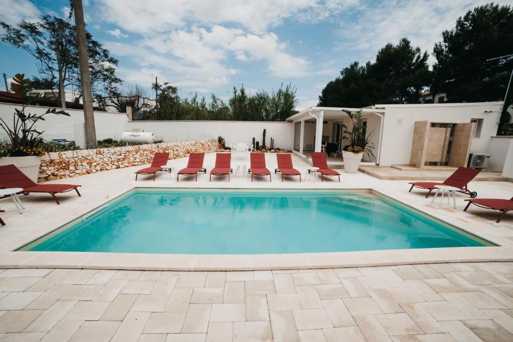 a swimming pool with red chairs and a patio at Le canne Pool and Relax in Pulsano