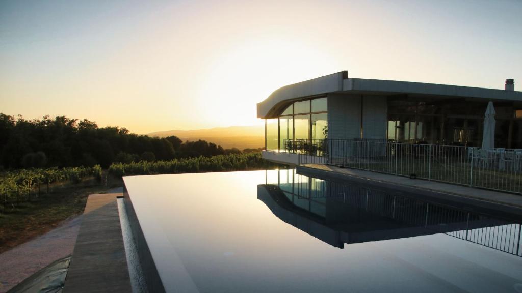 une maison sur l'eau avec le coucher du soleil en arrière-plan dans l'établissement Cincinnato Wine Resort, à Cori