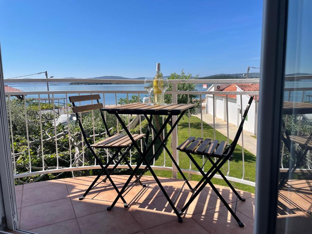 una mesa con 2 sillas y una botella de vino en el balcón en Apartments Roko, en Turanj