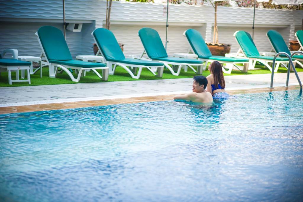 Guests relax in the pool beside a row of turquoise loungers.