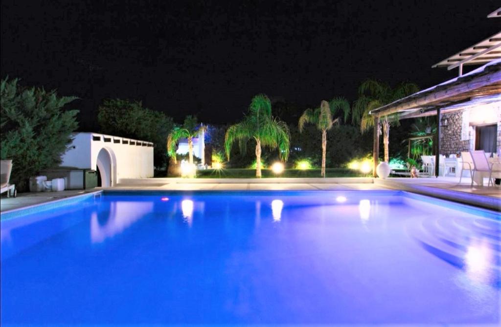 una piscina azul por la noche con una casa en White Diamond Villa, en Kamena Vourla