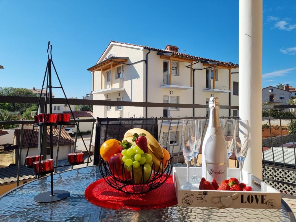a table with a bowl of fruit and a bottle of wine at Apartments Medulin - Orijeta in Medulin