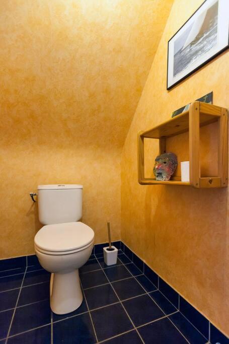 a bathroom with a white toilet in a yellow wall at Tous à l'ouest in Combrit