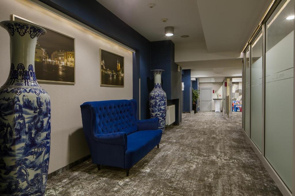 a hallway with a blue chair and two large vases at Hotel Centrum Business in Krakow