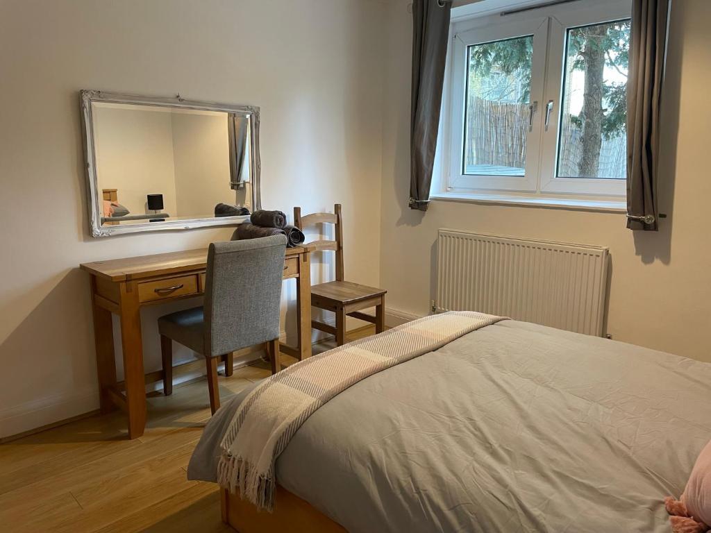 a bedroom with a desk and a bed with a mirror at Garden Flat in London