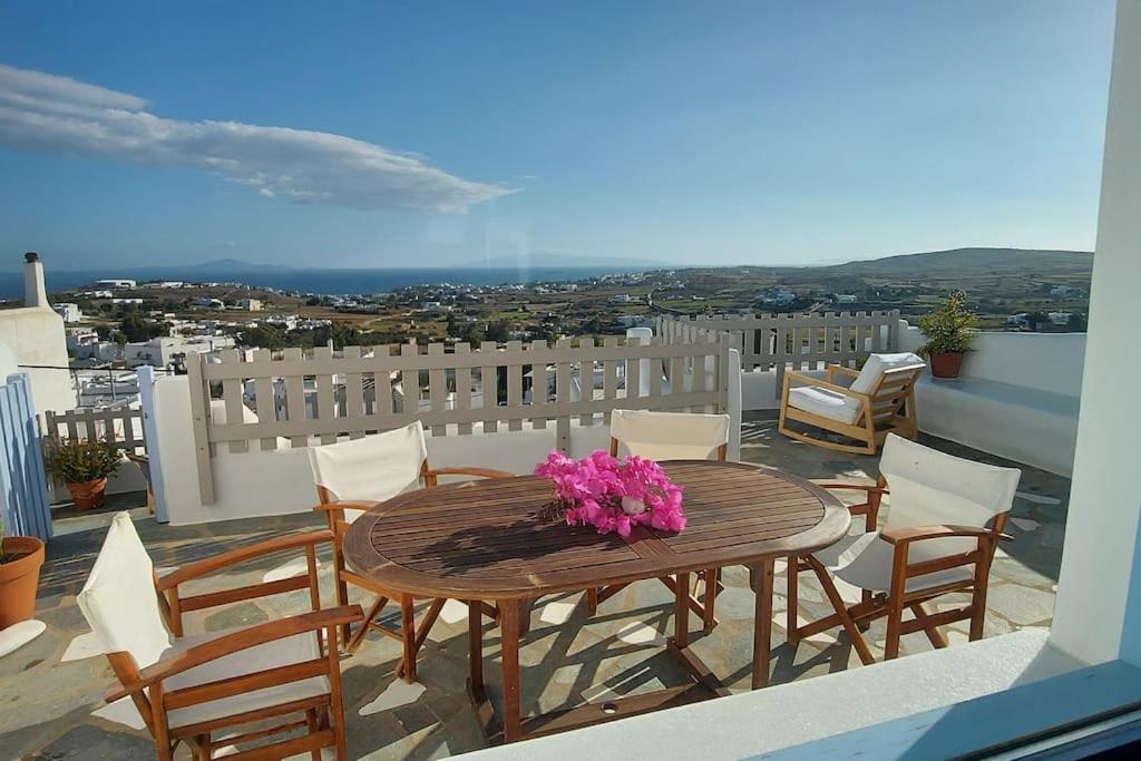 a wooden table with pink flowers on a balcony at L' Atelier, Marpissa Paros in Márpissa
