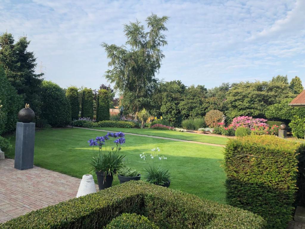 a garden with green grass and purple flowers and bushes at Vakantiehuis de wereldburger Worldcitizen in Oudsbergen 