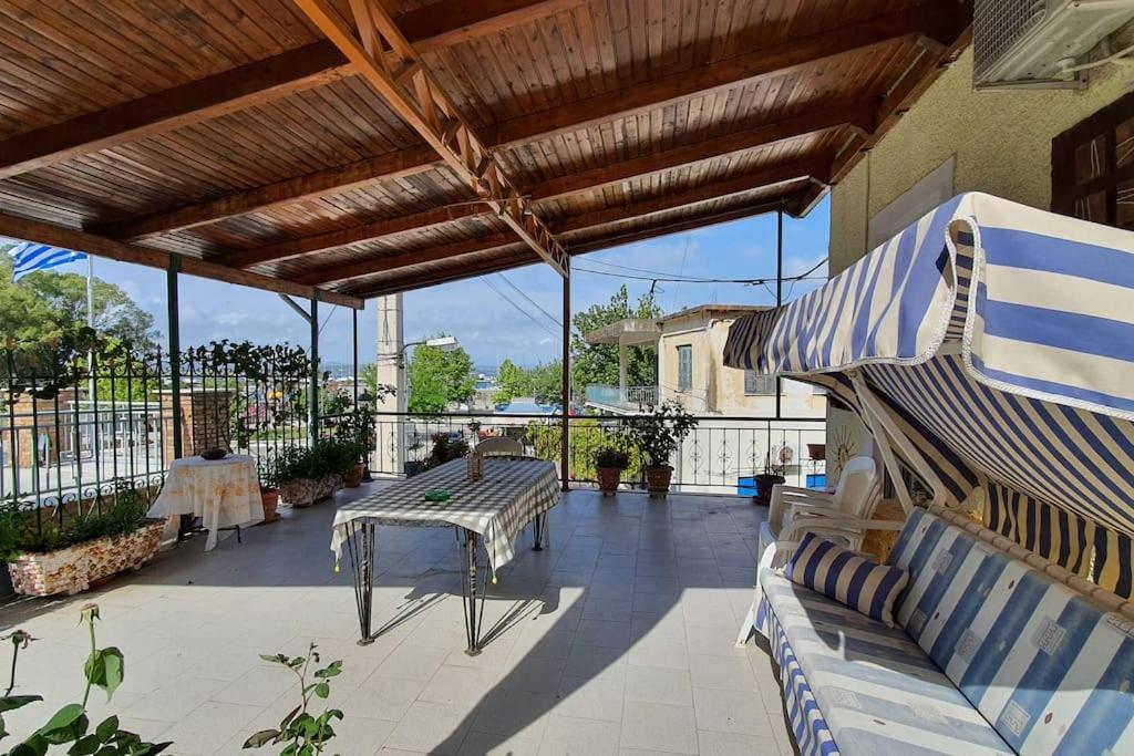 - une terrasse avec 2 bancs, une table et un parasol dans l'établissement Villa Galini, à Katakolon