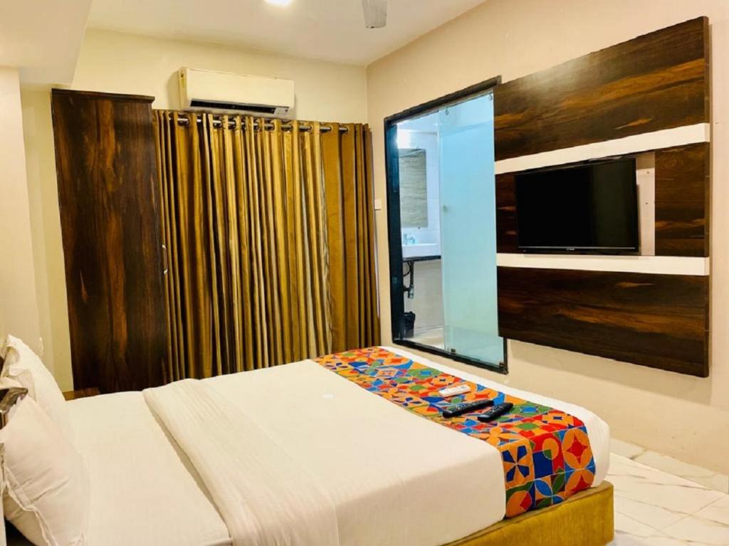 a bedroom with a bed and a large window with a tv at Hotel Embassy Park - BKC Mumbai in Mumbai