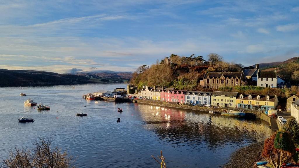 a river with buildings and boats in the water at Pink House Skye in Portree