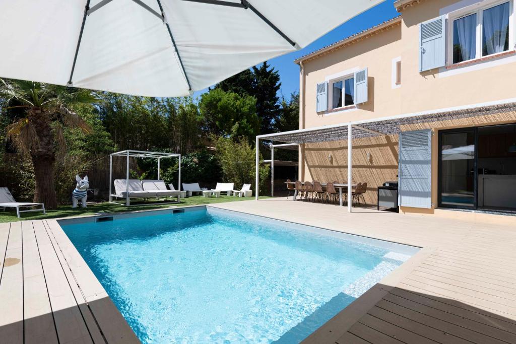 a swimming pool with an umbrella next to a house at Villa Acacias - Au coeur de Saint-Tropez in Saint-Tropez