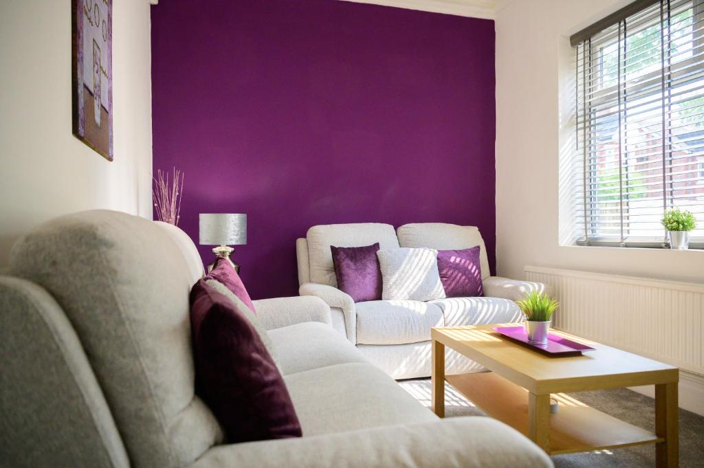 uma sala de estar com dois sofás e uma parede roxa em Purple Blossom, cosy 2 bed apartment, near Didsbury, free parking em Manchester