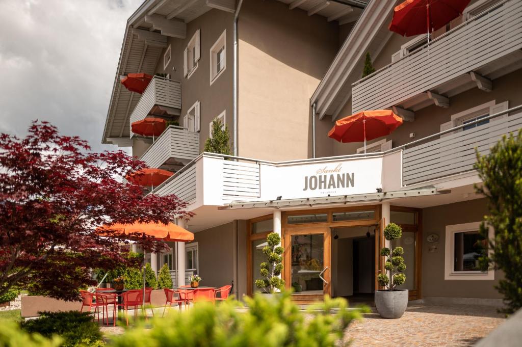 ein Hotel mit orangefarbenen Sonnenschirmen außerhalb des Hotels in der Unterkunft Sankt Johann Spa Suites & Apartments in Prad am Stilfserjoch