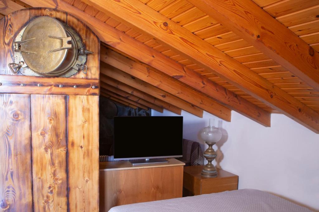 sypialnia z drewnianą ścianą z zegarem i telewizorem w obiekcie Captain Ikaros w Agios Kirykos