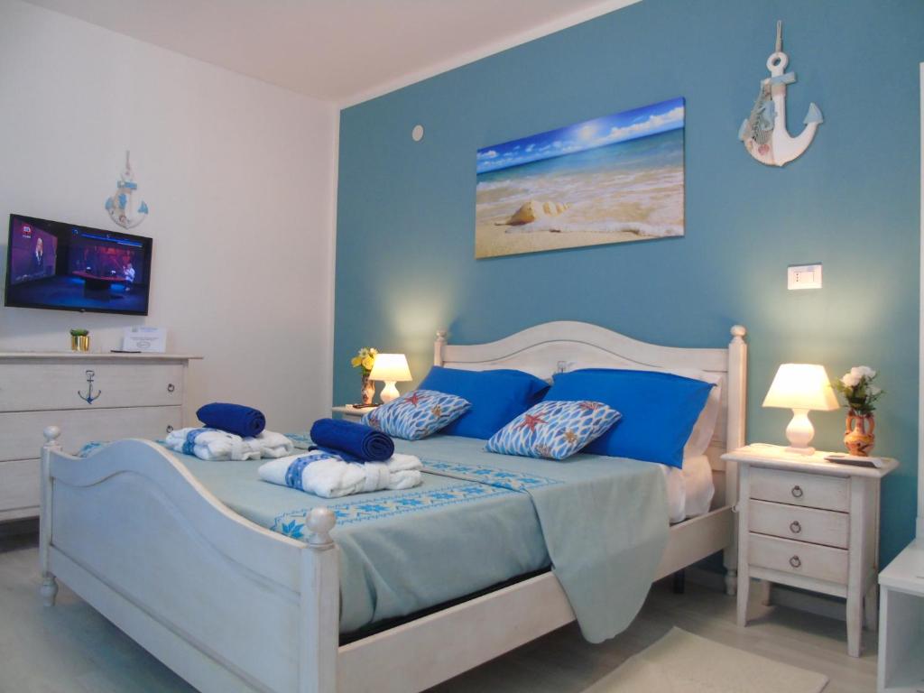 - une chambre avec des murs bleus et un lit avec des oreillers bleus dans l'établissement Affittacamere LiKele, à Castelsardo