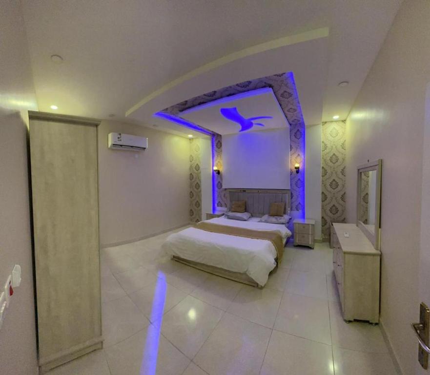 Dormitorio con cama con iluminación púrpura en شاليهات الفخامة en Ḑubā