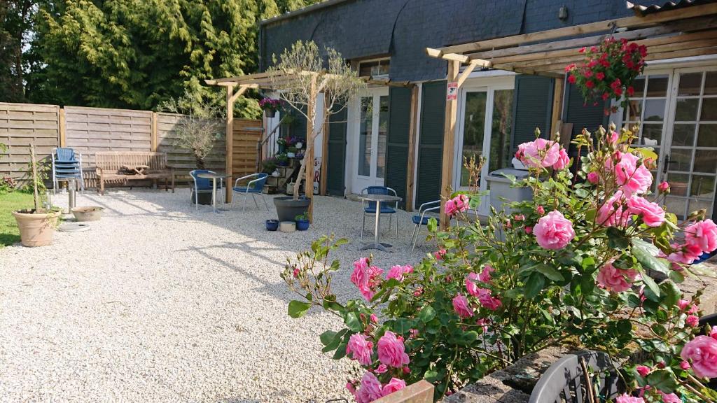 un patio con flores rosas y una casa en Le Black Dog Pub en Saint-Aignan