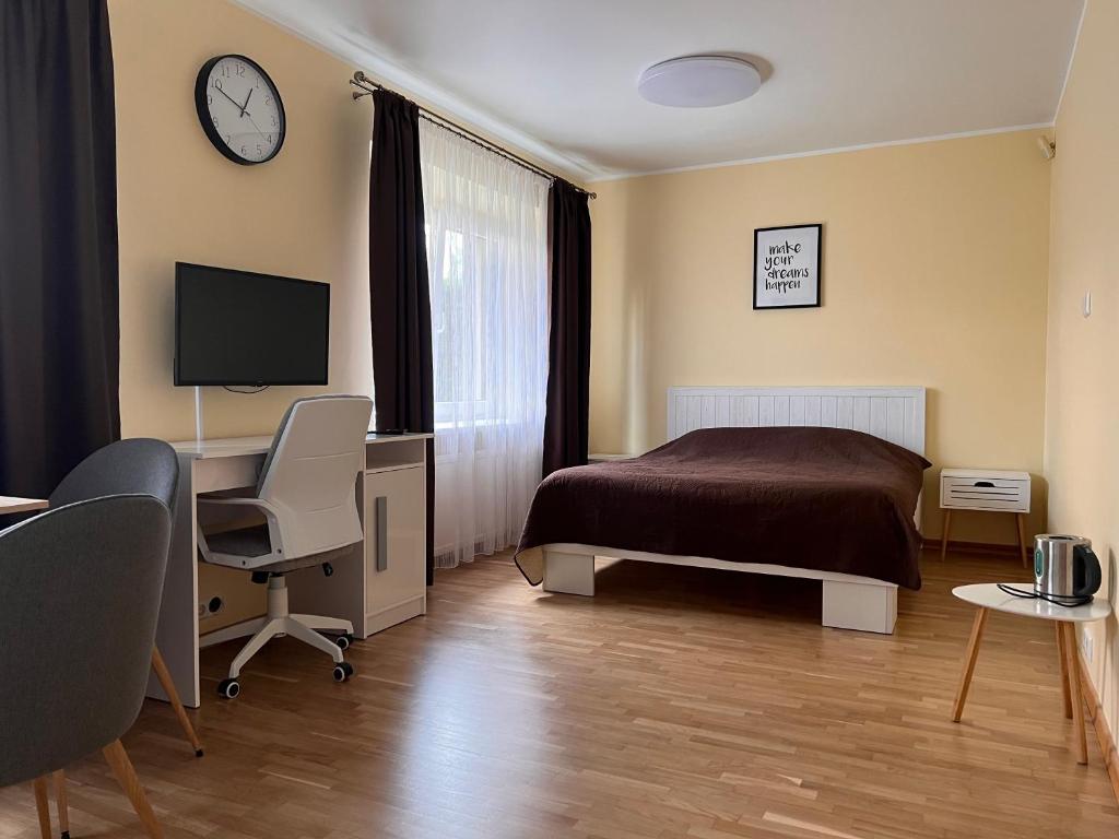 a bedroom with a bed and a desk and a tv at Kepezinski ECO Apartments in Kaunas
