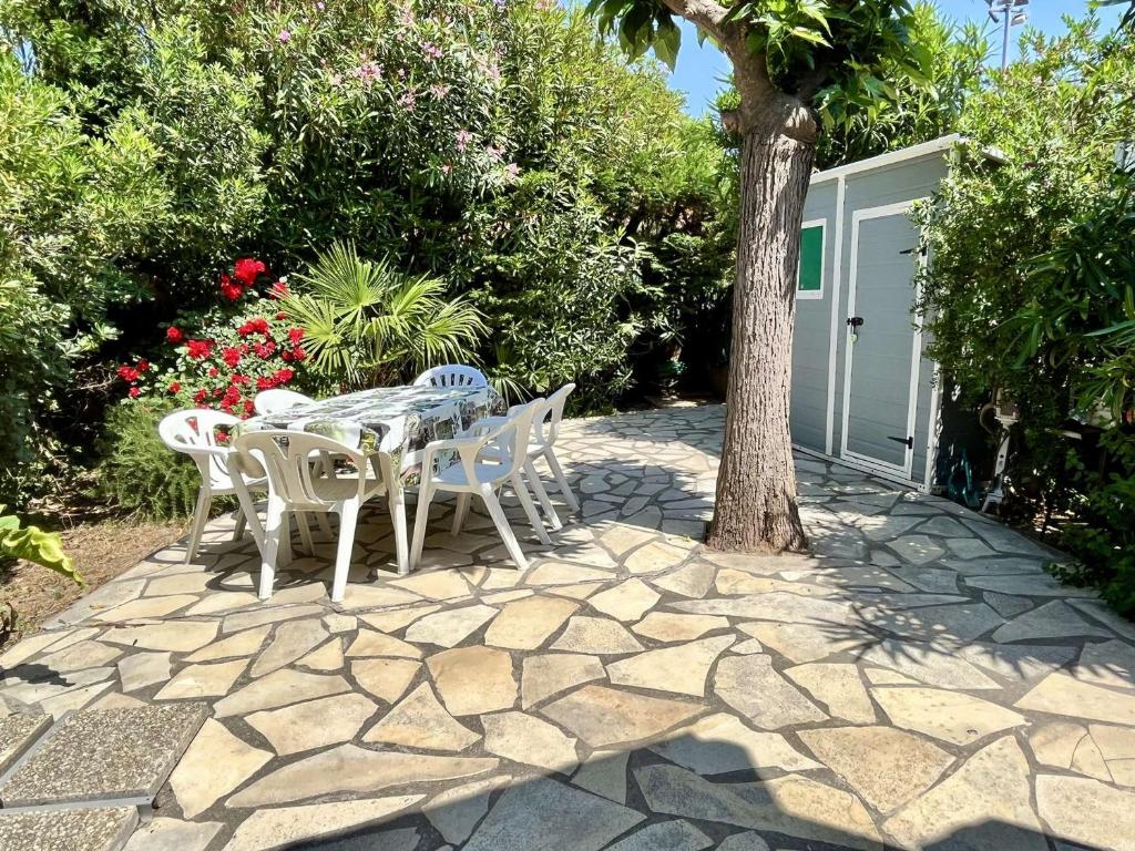 d'une terrasse avec une table, des chaises et un arbre. dans l'établissement Maison 3 pièces + mezzanine, climatisée, proche mer, parking privé, animaux acceptés - FR-1-225-224, à Argelès-sur-Mer