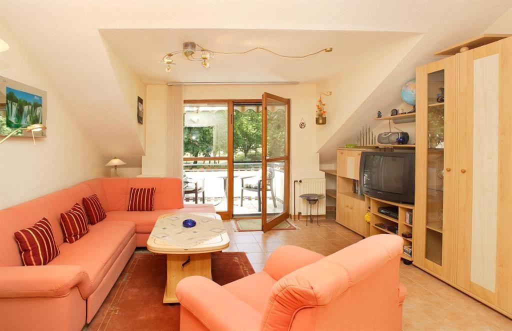 sala de estar con sofás naranjas y TV en An der Seeve, Ferienhaus, en Jesteburg
