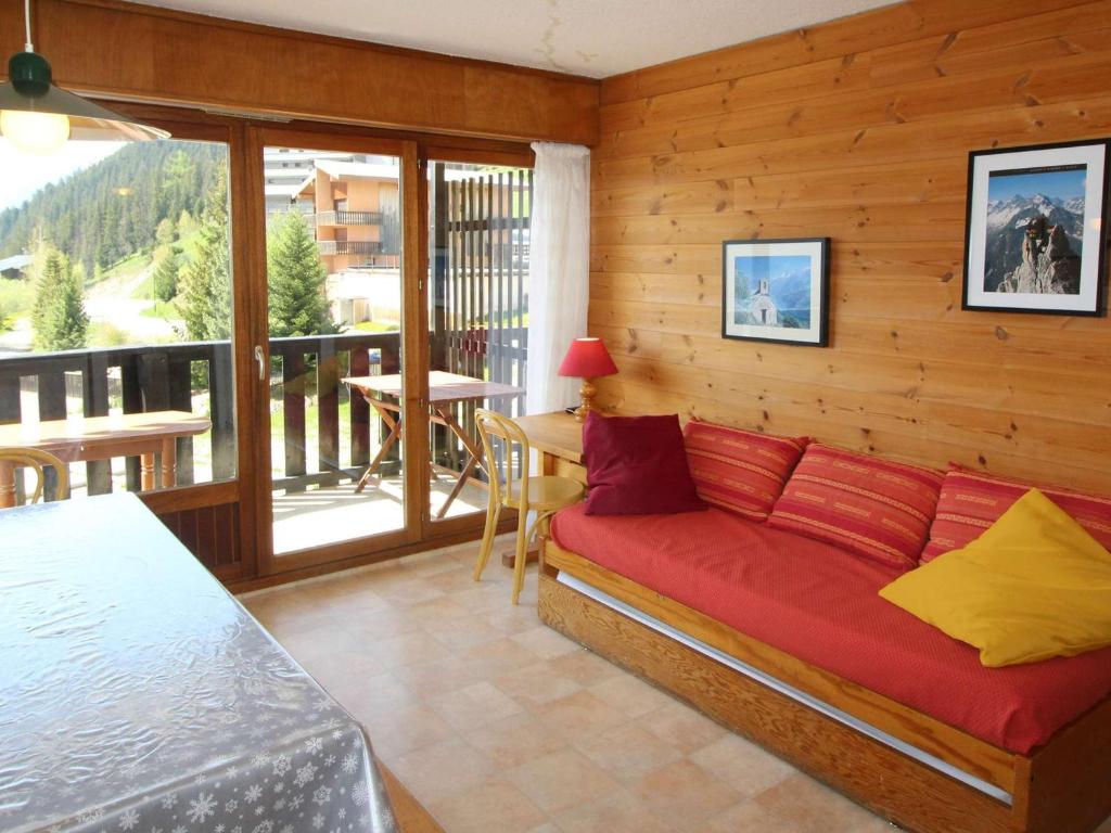 a bedroom with a red couch and a balcony at Appartement Auris, 3 pièces, 6 personnes - FR-1-297-27 in Auris