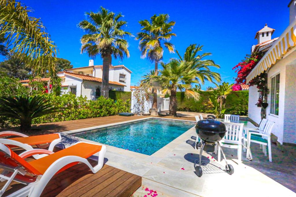 a swimming pool with chairs and a grill next to a house at Villa Monet ONLY FAMILIES in Cambrils