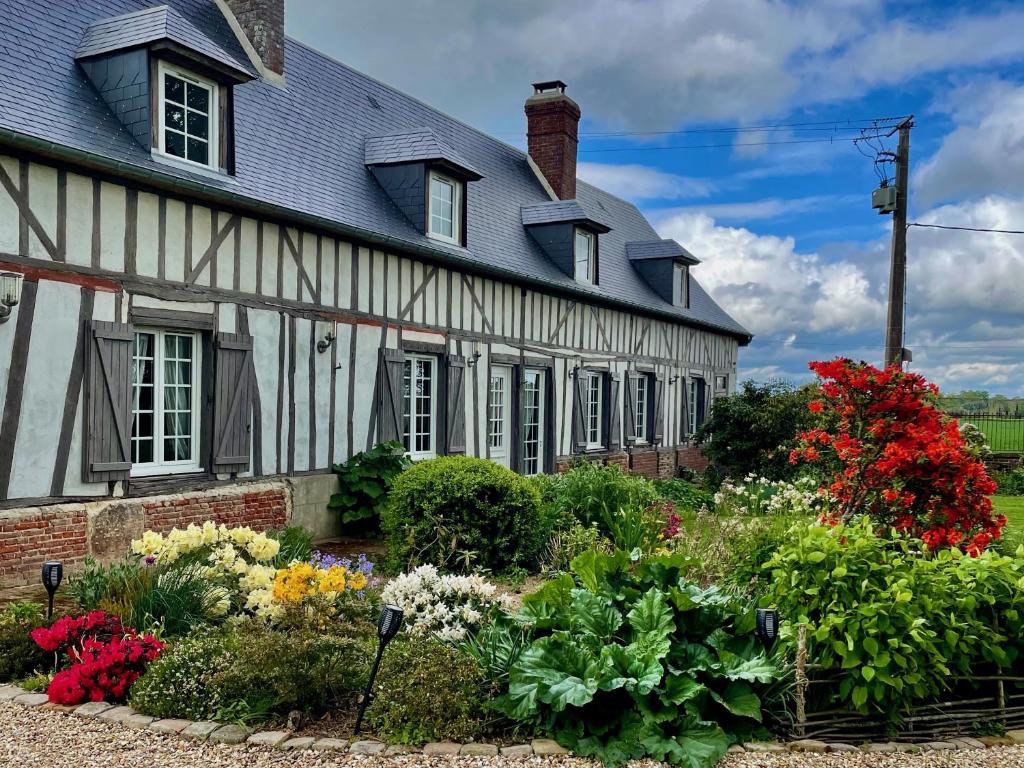 un jardin avec des fleurs en face d'une maison dans l'établissement Cottage 4 chambres avec cheminée, à Épégard