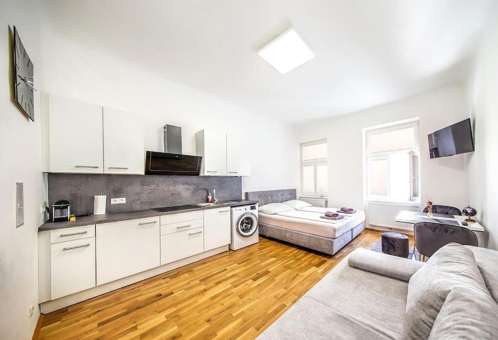a kitchen with white cabinets and a living room at Cozy apartment Studio in Vienna