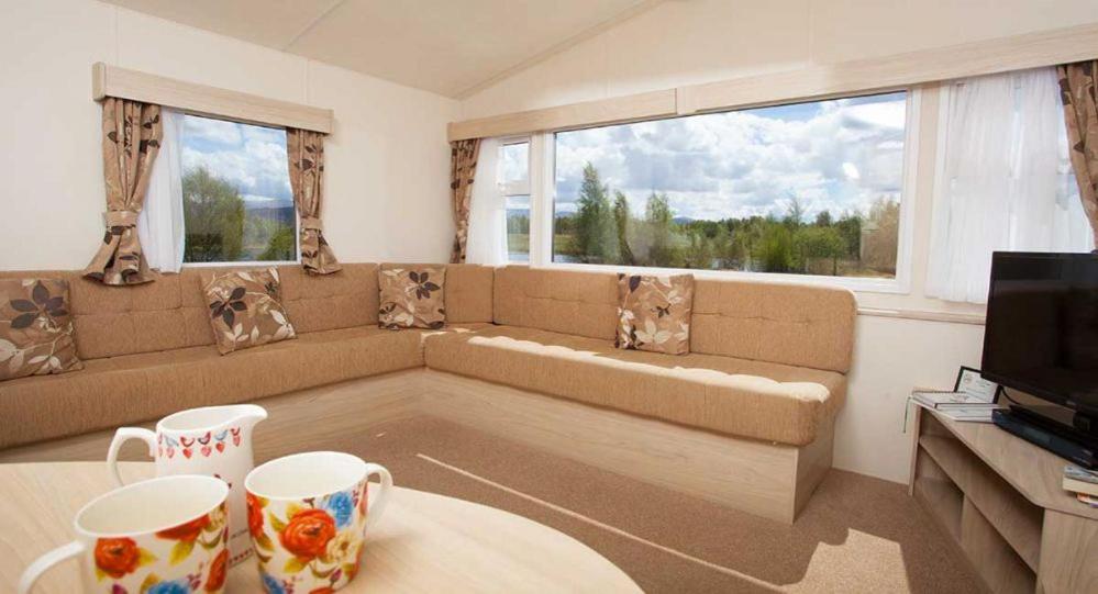 a living room with a couch and two cups on a table at The Hide near Aviemore in Aviemore