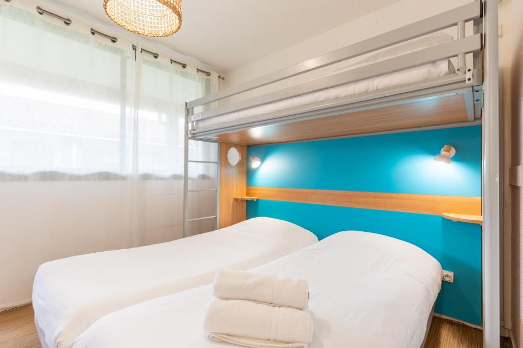 - une chambre avec 2 lits superposés et un mur bleu dans l'établissement Kyriad Direct Bordeaux Sud Cestas, à Cestas