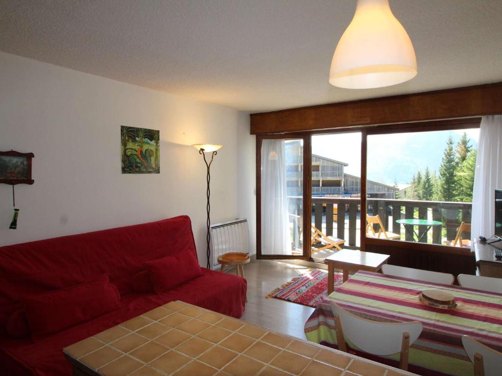 a living room with a red couch and a large window at Appartement Auris, 1 pièce, 4 personnes - FR-1-297-331 in Auris