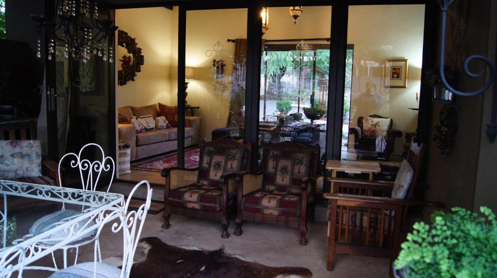 a living room with chairs and a mirror at Cunningham Cottage Guest House in Kuruman