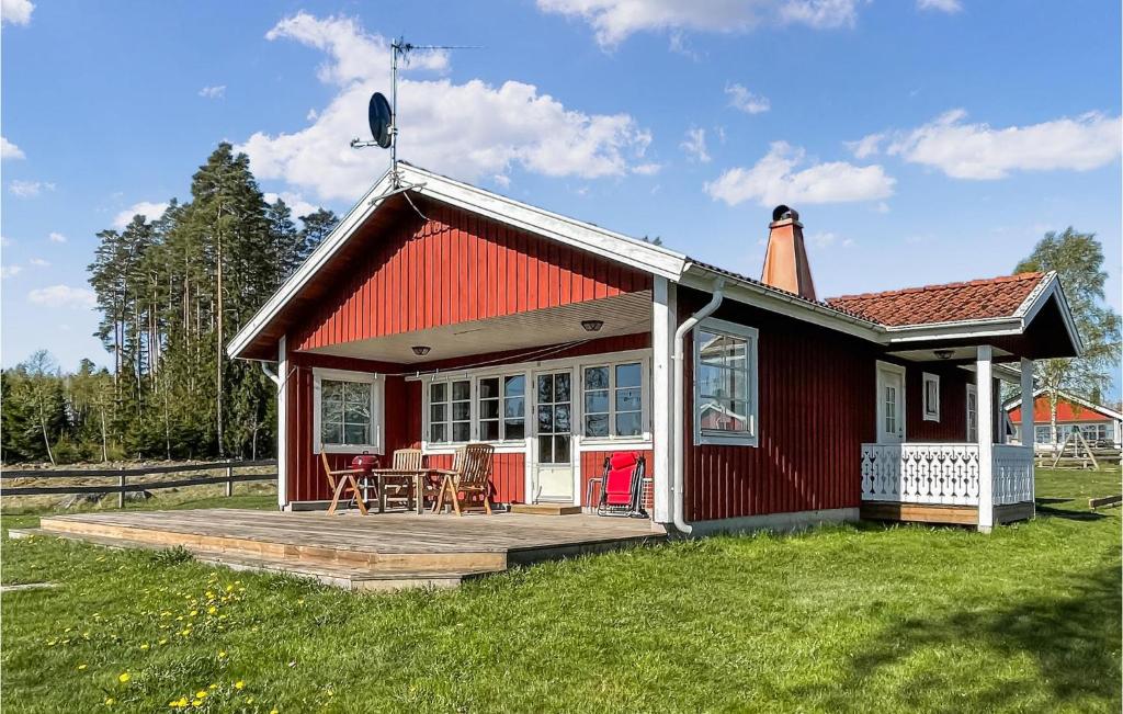 una casa roja con una terraza de madera en el césped en Beautiful home in Vittaryd with 3 Bedrooms and WiFi, en Kvänarp